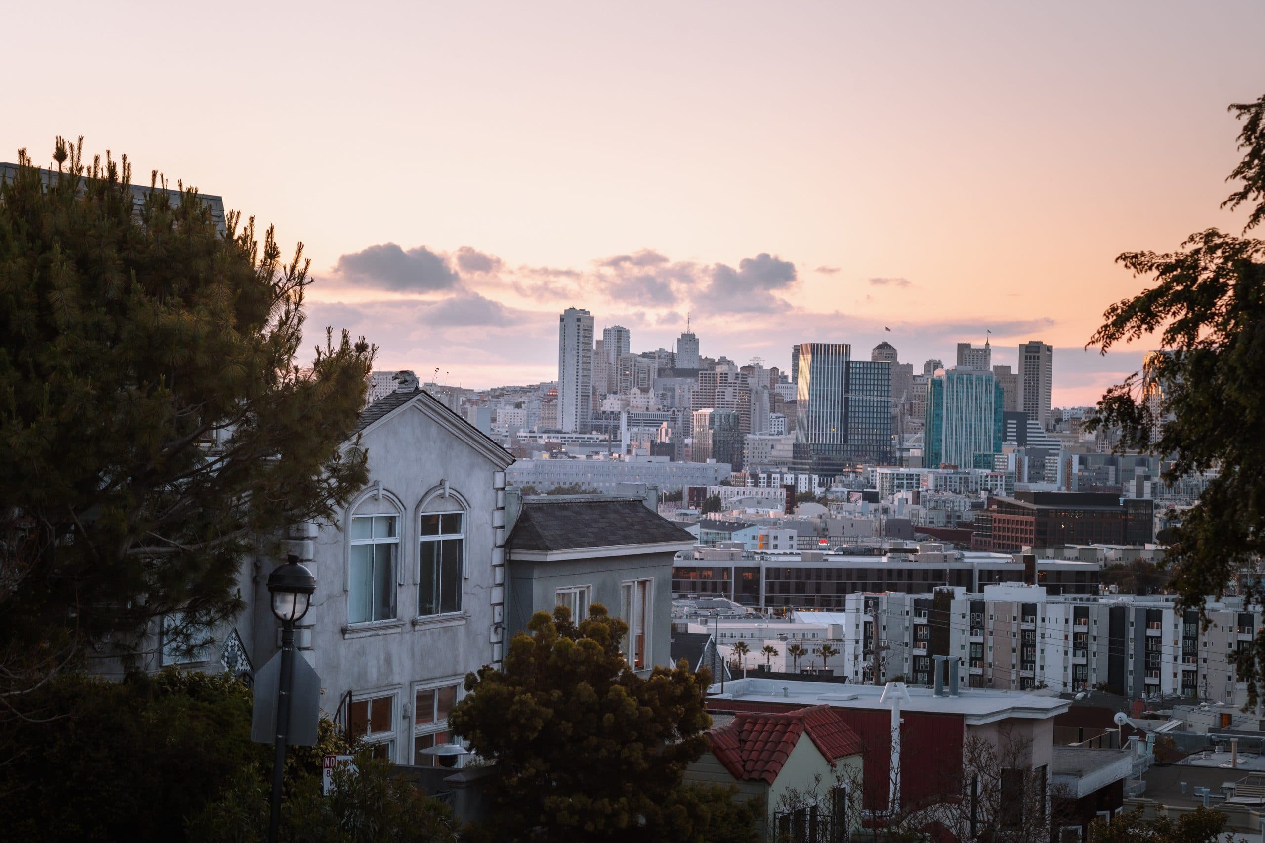 Photo of San Francisco at sunset, photographed from a hill on a residential street. 