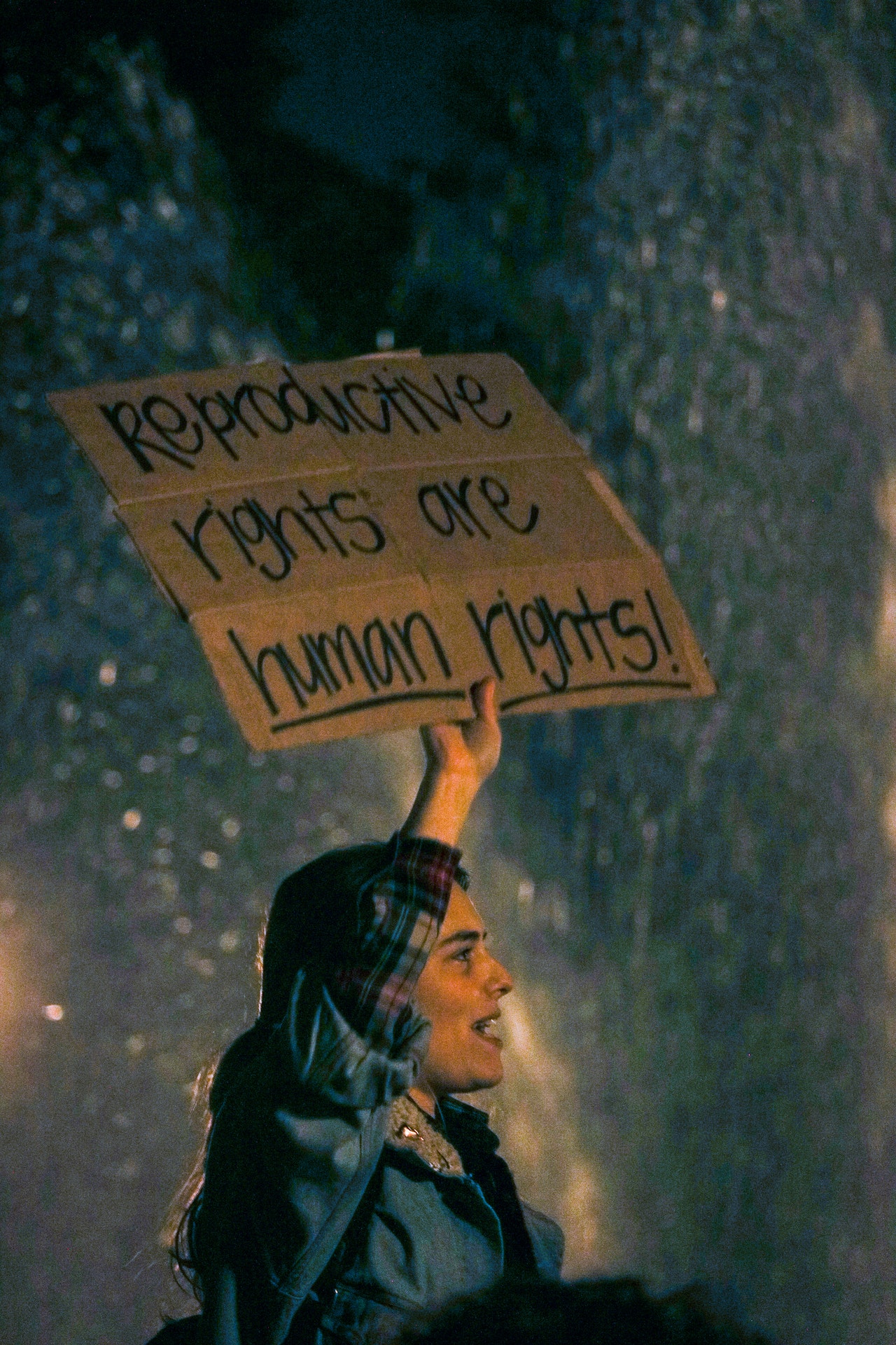 Person at a nighttime pro abortion rights protest holding up a sign that says "Reproductive Rights are Human Rights"