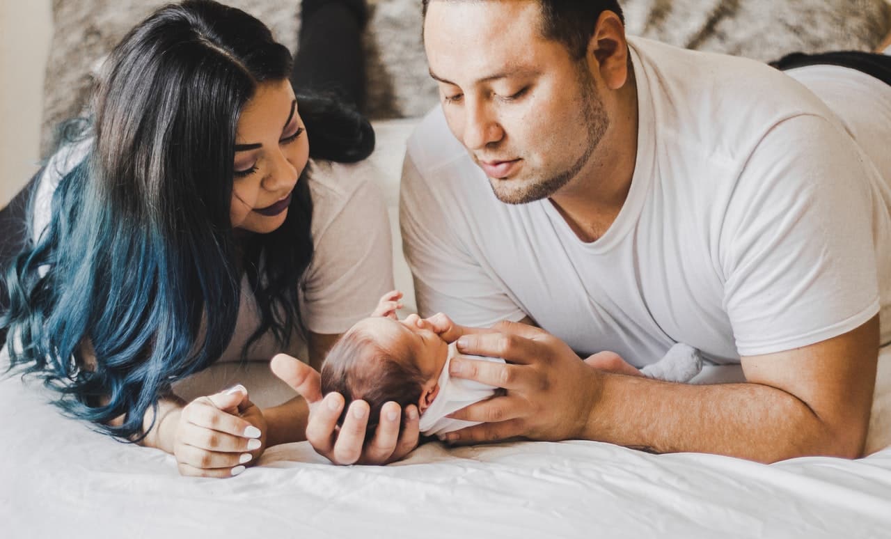 Two parents looking over their newborn with serious expressions on their faces.