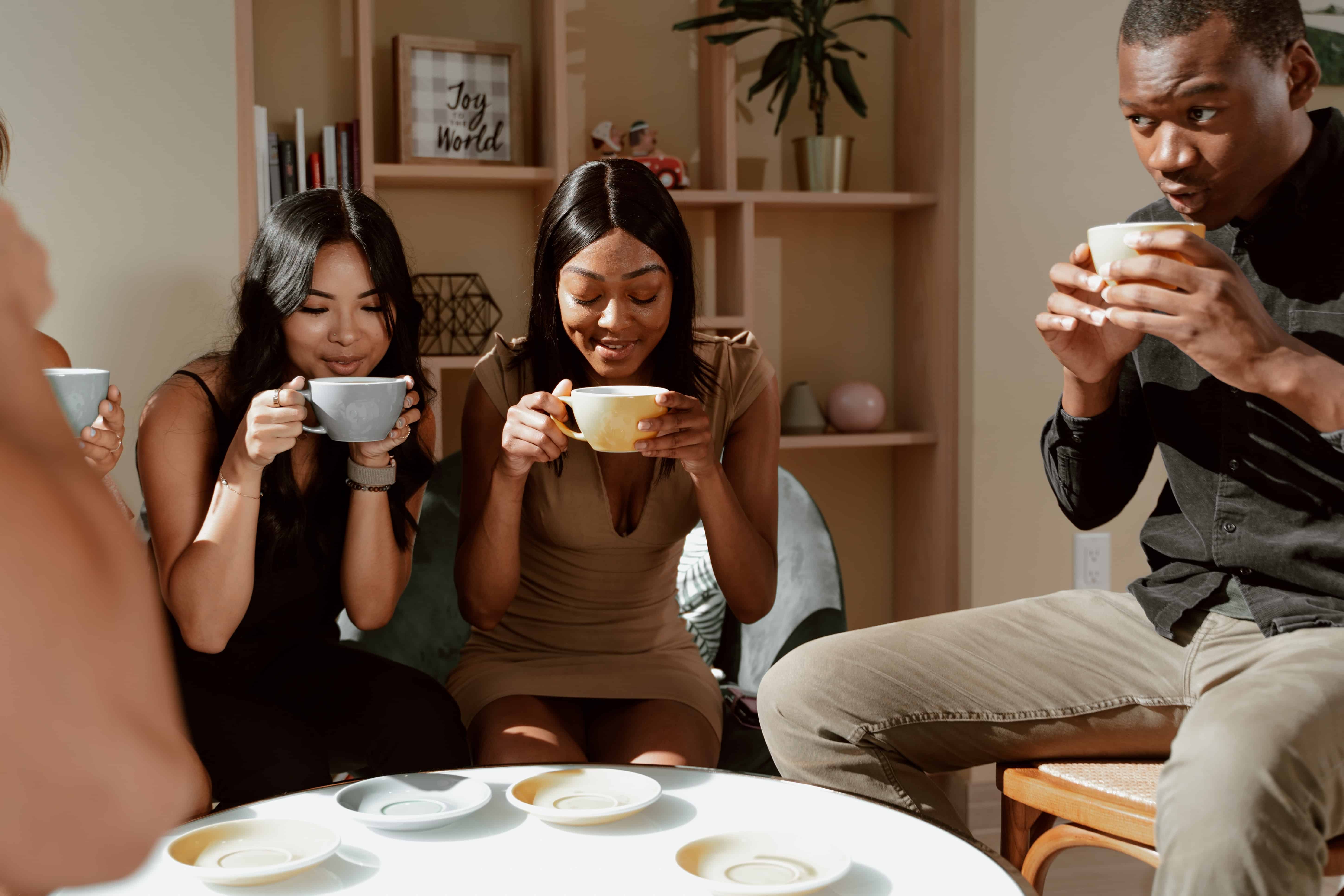 A group of friends drinking tea together in a living room. 
