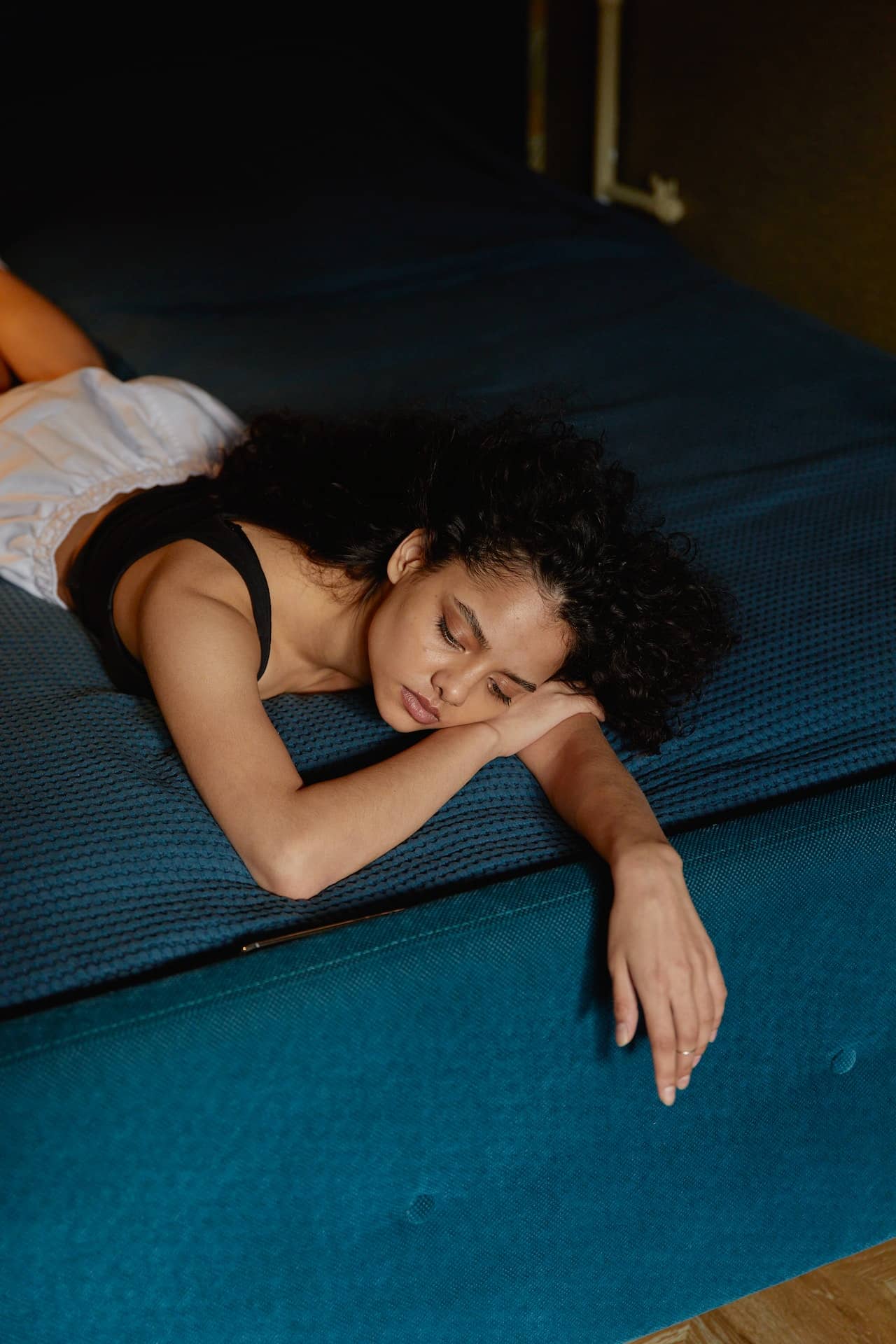 A woman lying on her stomach sleeping in a crop top and shorts.