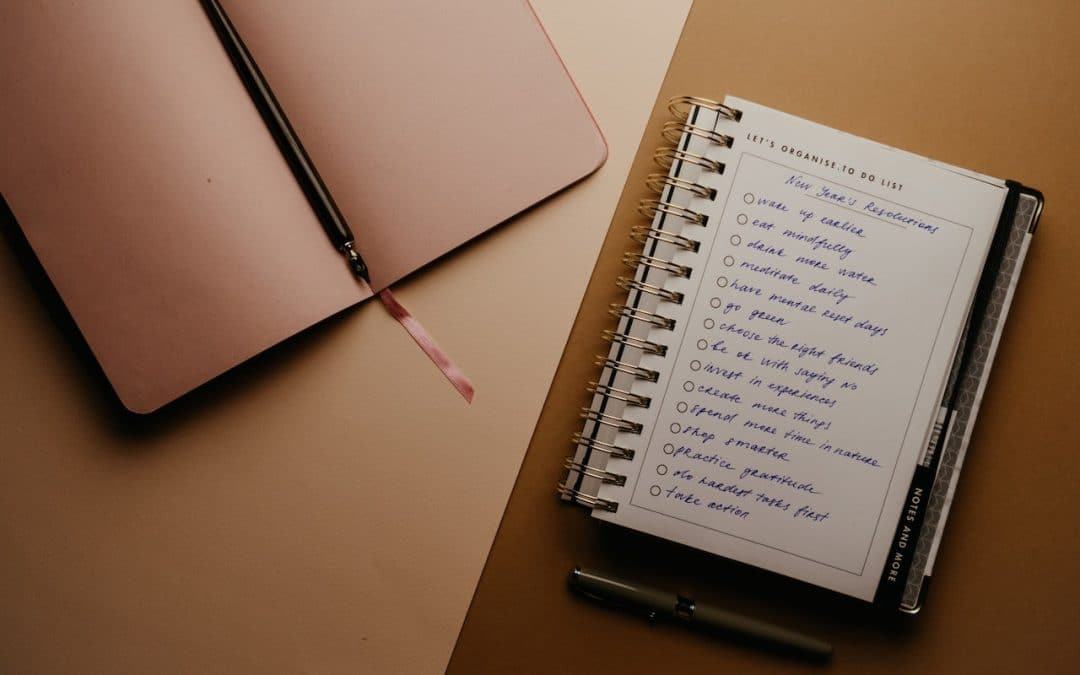 Photo of a notebook open with long list of new years goals, such as "do the hardest taxes first", "eat mindfully", and "go green".