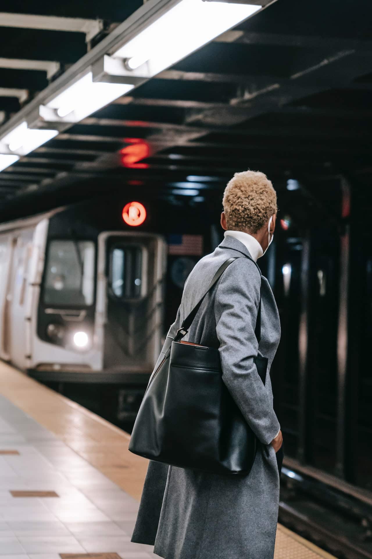 Black woman with short natural hair waits for the subway