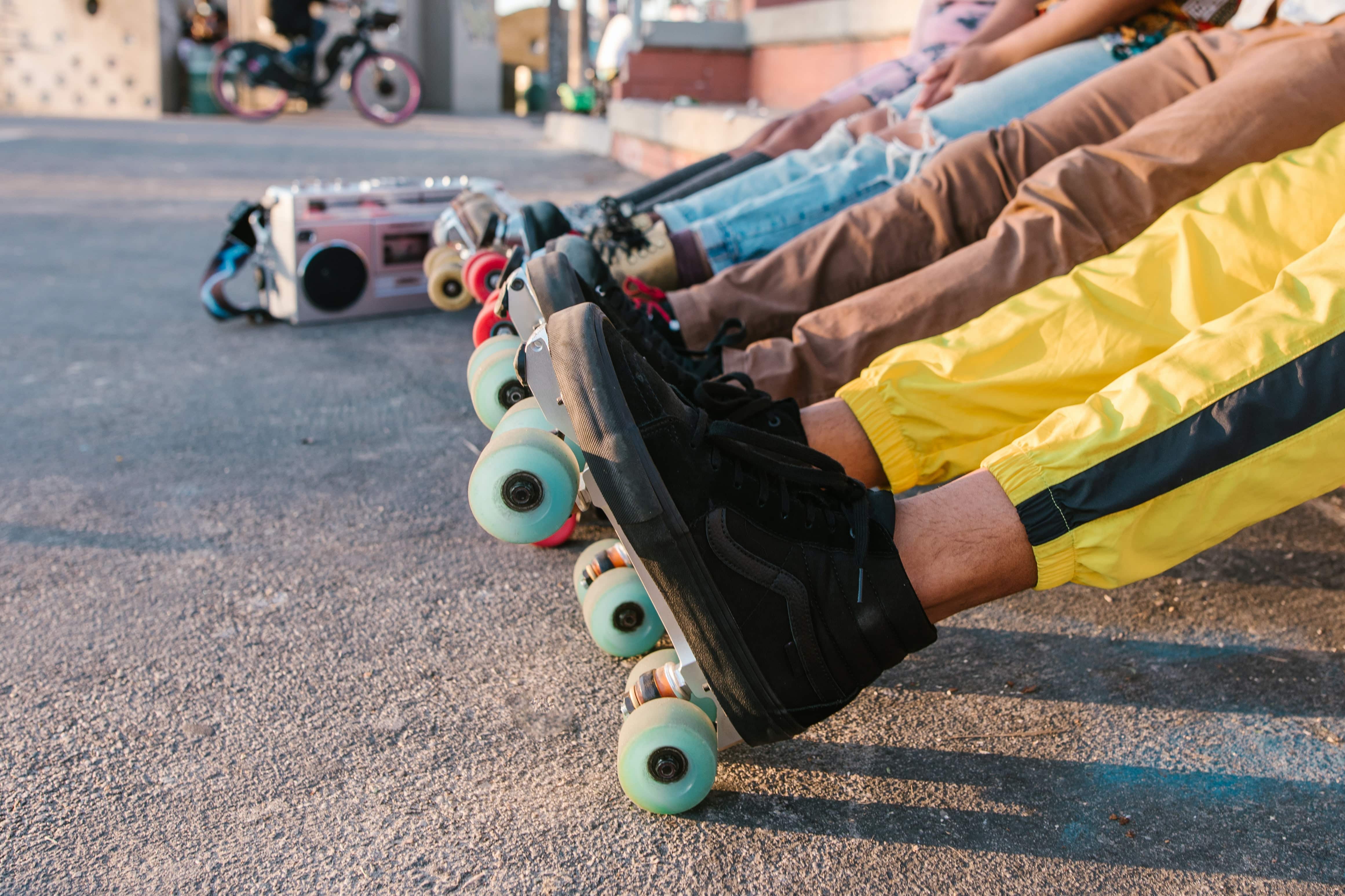 A photo showing a lineup of people's legs wearing roller skates on pavement. 