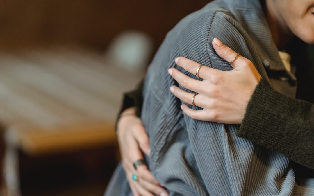 Hands wrapped around a body in a comforting hug.