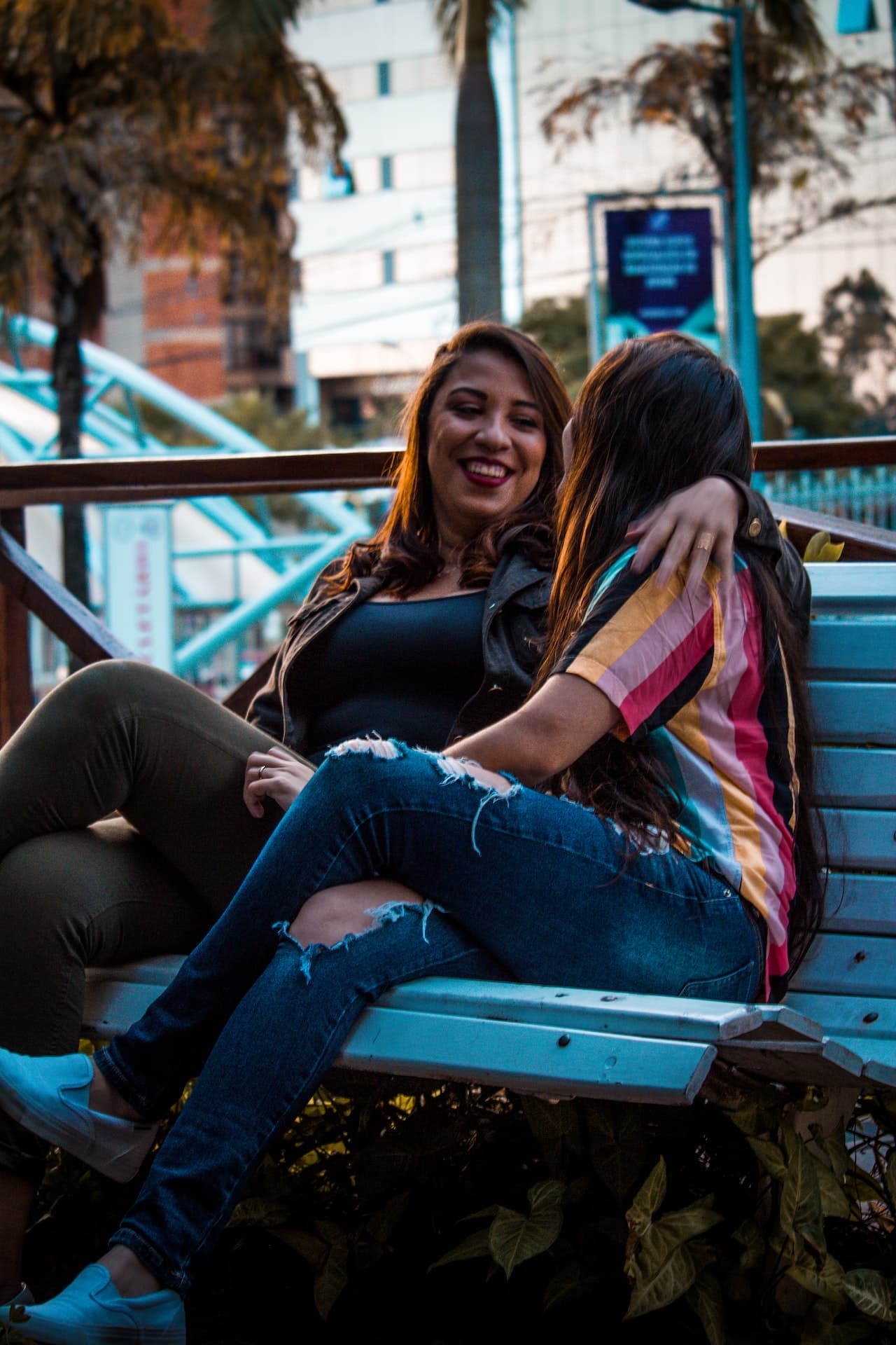 A queer couple relaxed hanging out on a park bench around sunset