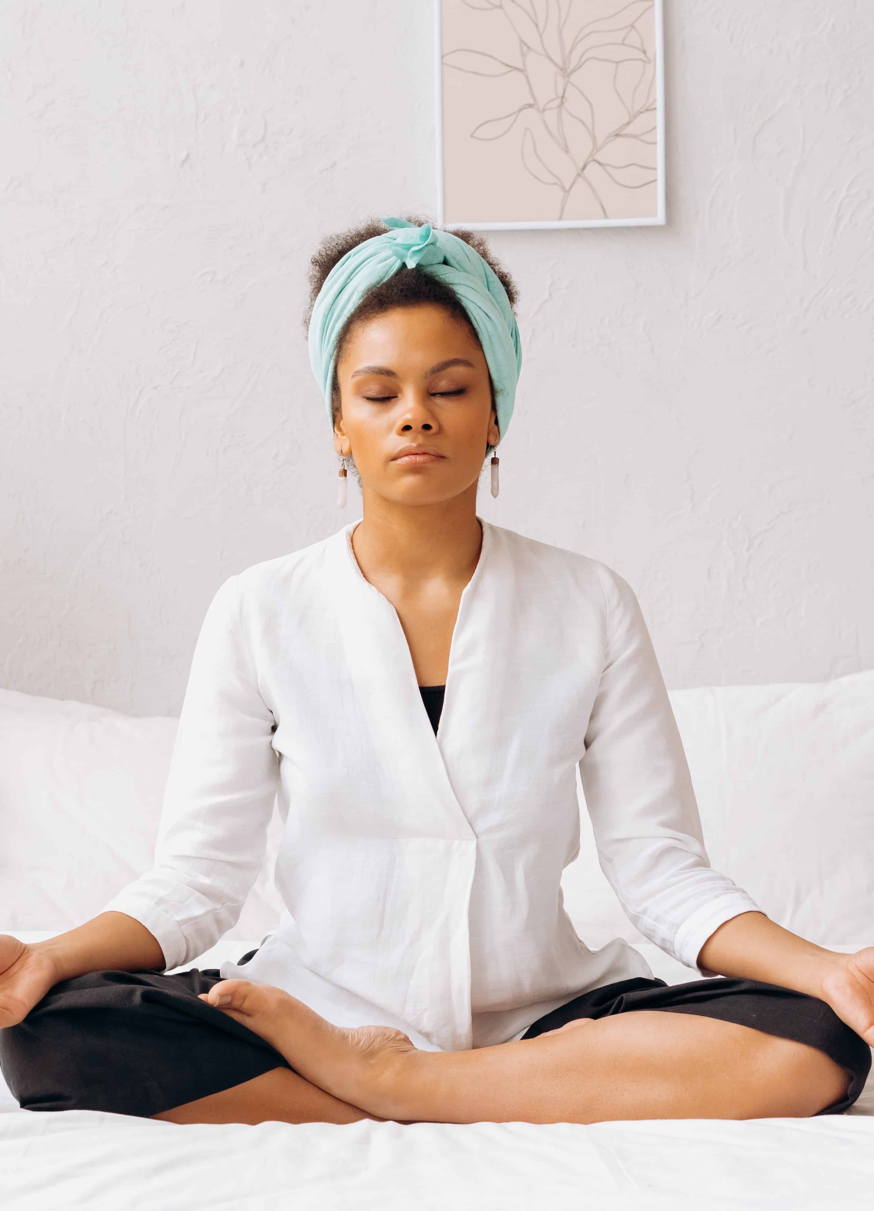 Stock photo of relaxed, black woman meditating with eyes closed.