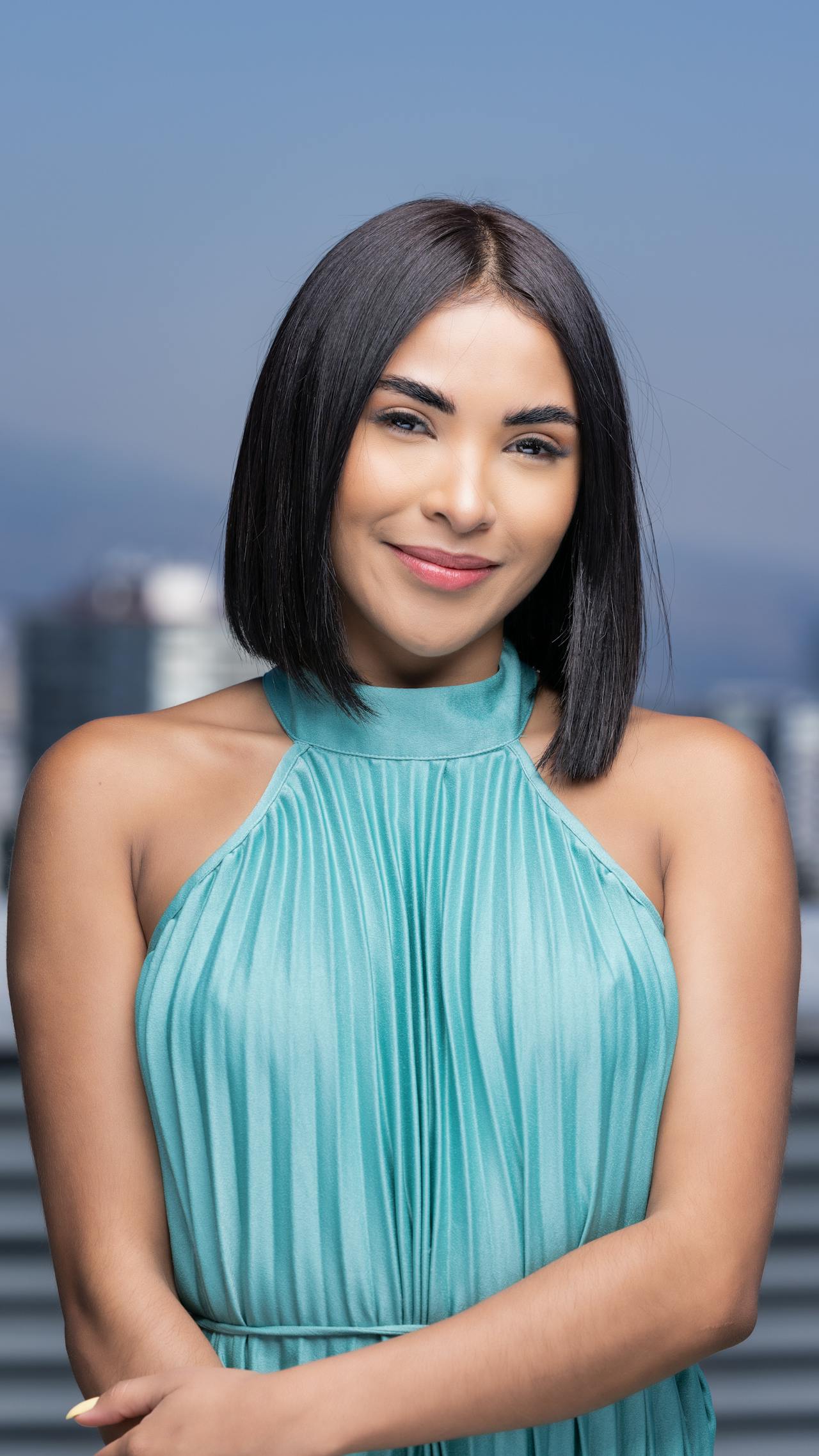 A woman with medium complexion and short dark bob, wearing a blue blouse.